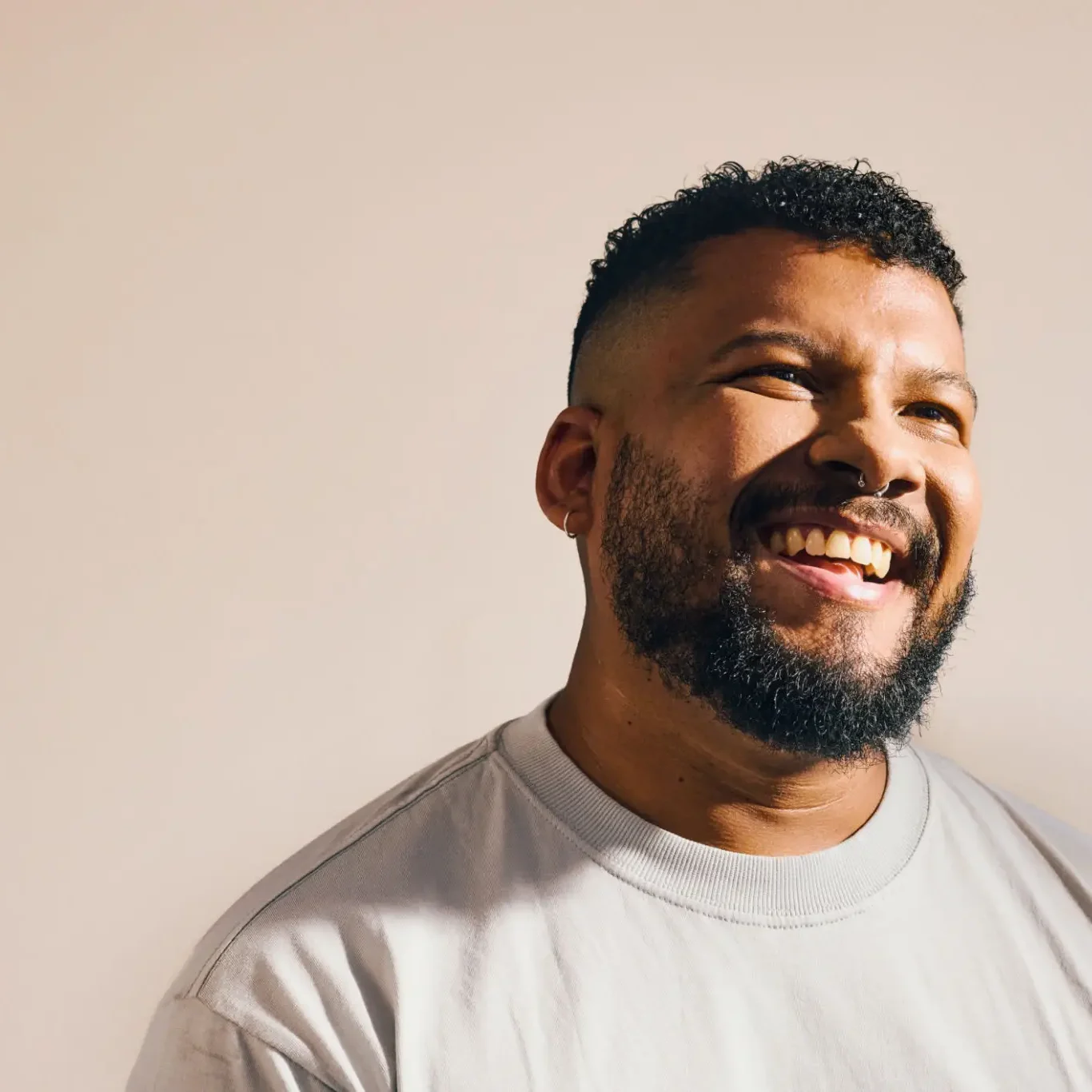 Smiling man with beard and short hair wearing a white t-shirt.
